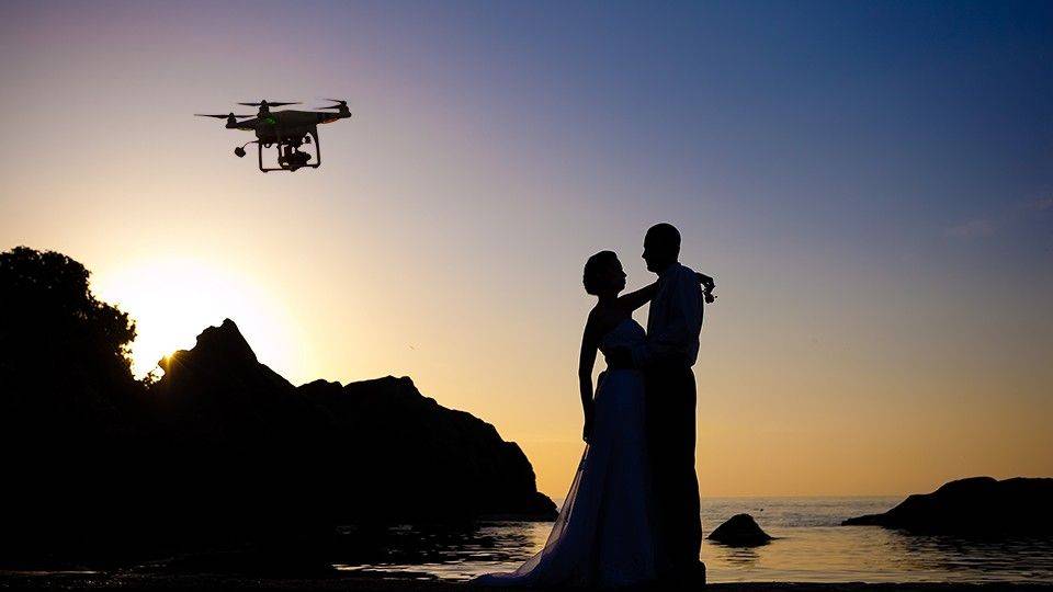 silueta de pareja al atardecer y drone volando