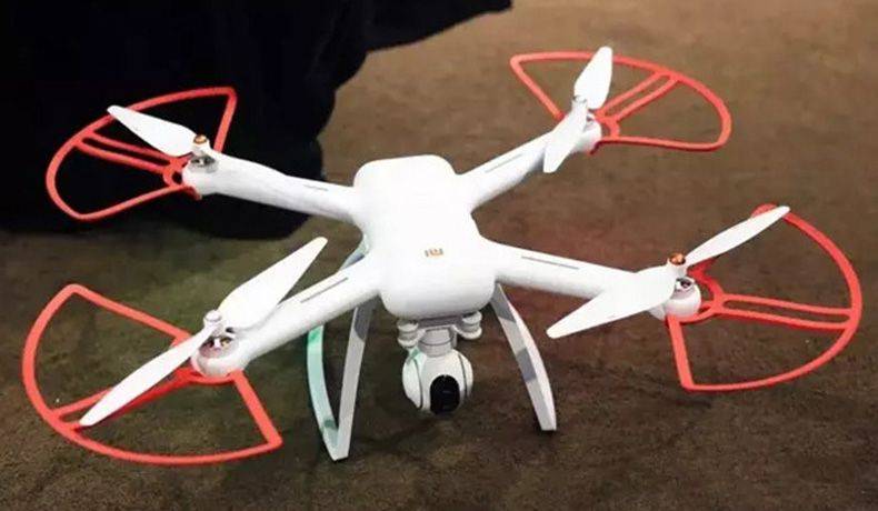 drone blanco y naranja reposando en el suelo