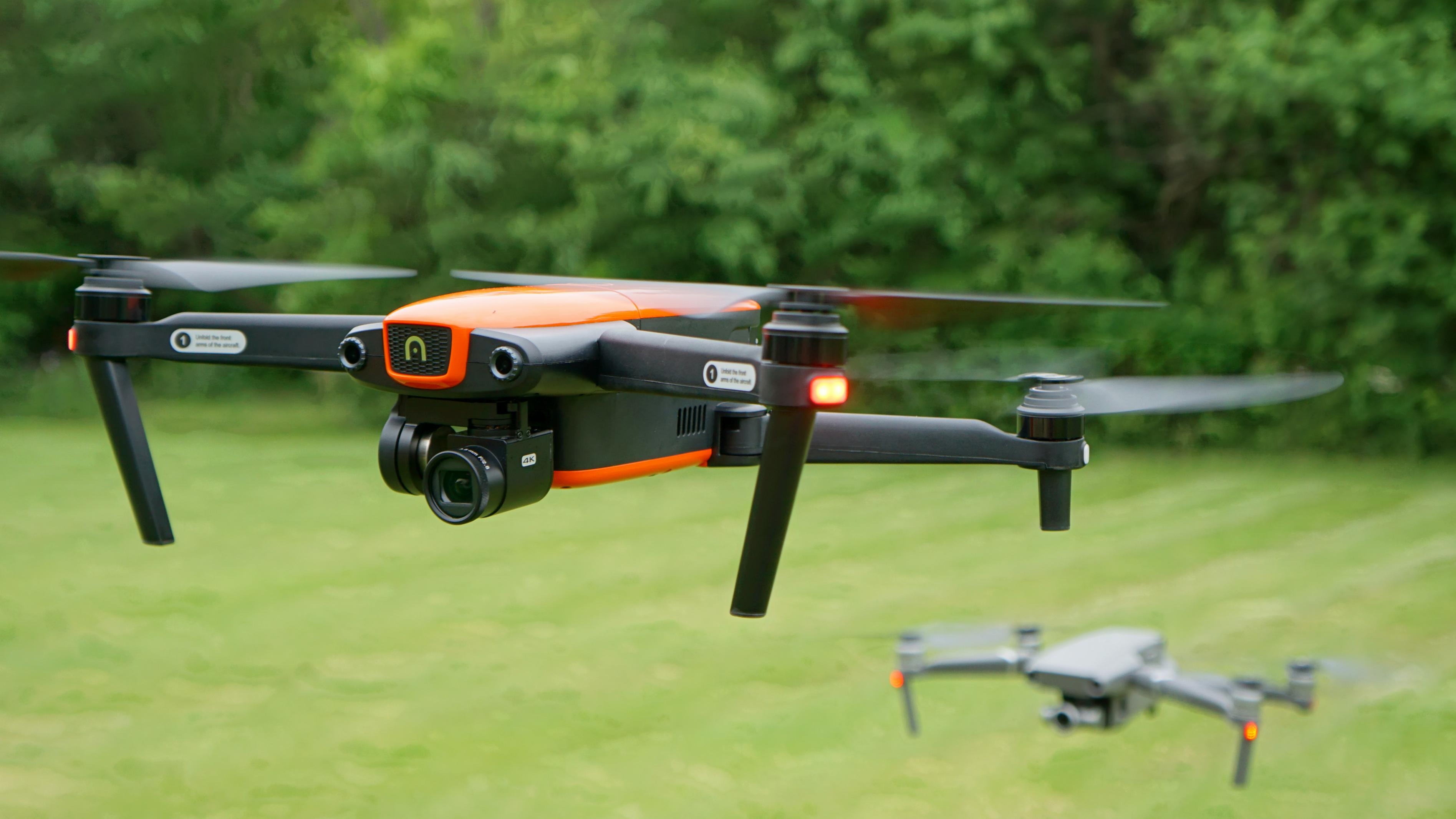 Drone naranja y negro sobrevolando un pastizal
